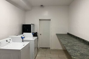 Ein Waschraum mit Waschmaschine, Trockner und einem kleinen Kühlschrank.