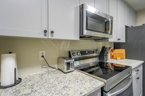 Eine Küche mit weißen Schränken, einer Edelstahl-Mikrowelle, einem Toaster und einem Herd.