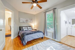 A bedroom with a bed, a ceiling fan, a painting, and a view of the outdoors through a window. - 2 Mi to Augusta National: Walkable Neighborhood! (Augusta)