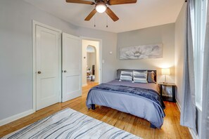 A bedroom with a bed, a ceiling fan, a nightstand, a lamp, and a painting on the wall. - 2 Mi to Augusta National: Walkable Neighborhood! (Augusta)