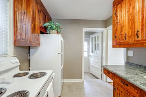 A kitchen with wooden cabinets, a white refrigerator, a stove, and a countertop. - 2 Mi to Augusta National: Walkable Neighborhood! (Augusta)