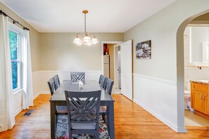 A dining room with a wooden table and chairs, a chandelier, and a view of the kitchen through an open door. - 2 Mi to Augusta National: Walkable Neighborhood! (Augusta)
