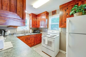A kitchen with wooden cabinets, a white stove, a refrigerator, and a microwave. - 2 Mi to Augusta National: Walkable Neighborhood! (Augusta)