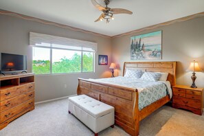 A bedroom with a bed, a TV, a ceiling fan, a window, and a painting on the wall. - Desert-View Green Valley Retreat Near Golf Courses (Green Valley)