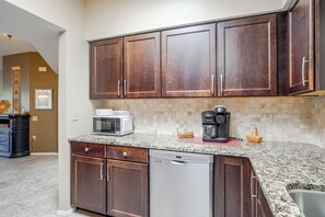 A kitchen with dark wooden cabinets, a microwave, a coffee maker, and a dishwasher. - Desert-View Green Valley Retreat Near Golf Courses (Green Valley)