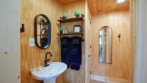 A wooden-paneled bathroom with a white sink, a mirror, and a towel rack.
