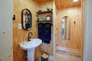 A wooden-paneled bathroom with a white sink, a mirror, and a towel rack. - Pond & Overlook! Cabin Near Blue Rock State Park (Blue Rock)
