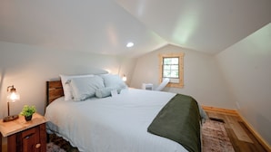 A bedroom with a bed, bedside table, lamp, and a window.