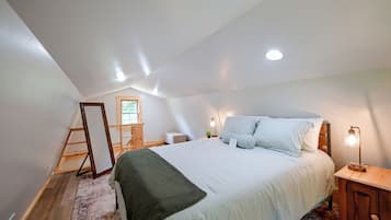 Un dormitorio con una cama grande, una escalera de madera, una mesita con una lámpara y una ventana.