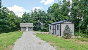 A gravel driveway leading to a two-story house with a small shed.