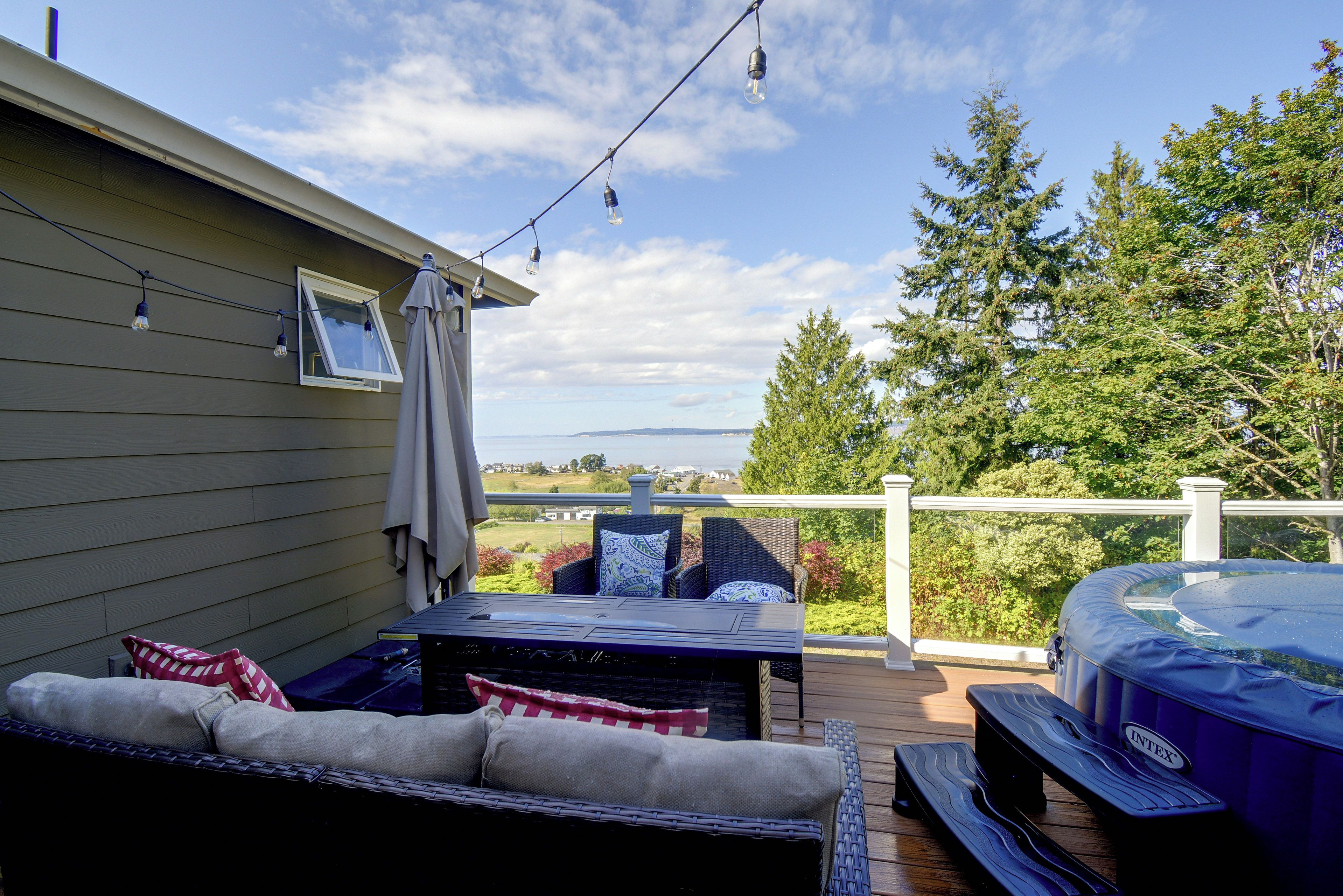 A deck with outdoor furniture, a hot tub, and a view of the landscape.