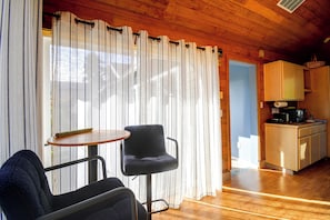 A room with a wooden ceiling, a dining table with two chairs, a kitchen area with a microwave, and a window with curtains. - Walk to Beach! Kitsap Coast Retreat w/ Hot Tub (Hansville)