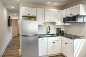 A modern kitchen with white cabinetry, a stainless steel refrigerator, a microwave, and a coffee maker.