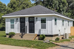 A single-story house with a front porch, a black front door, and a chimney.