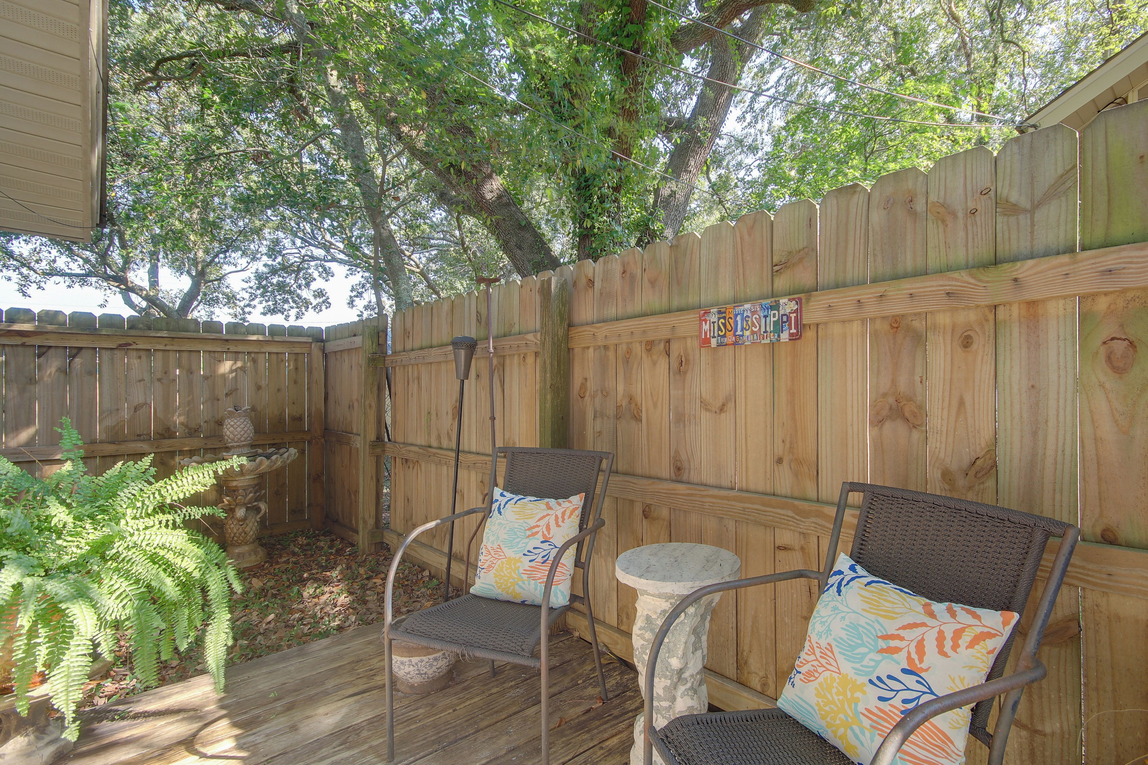A wooden deck with two wicker chairs and a small round table.