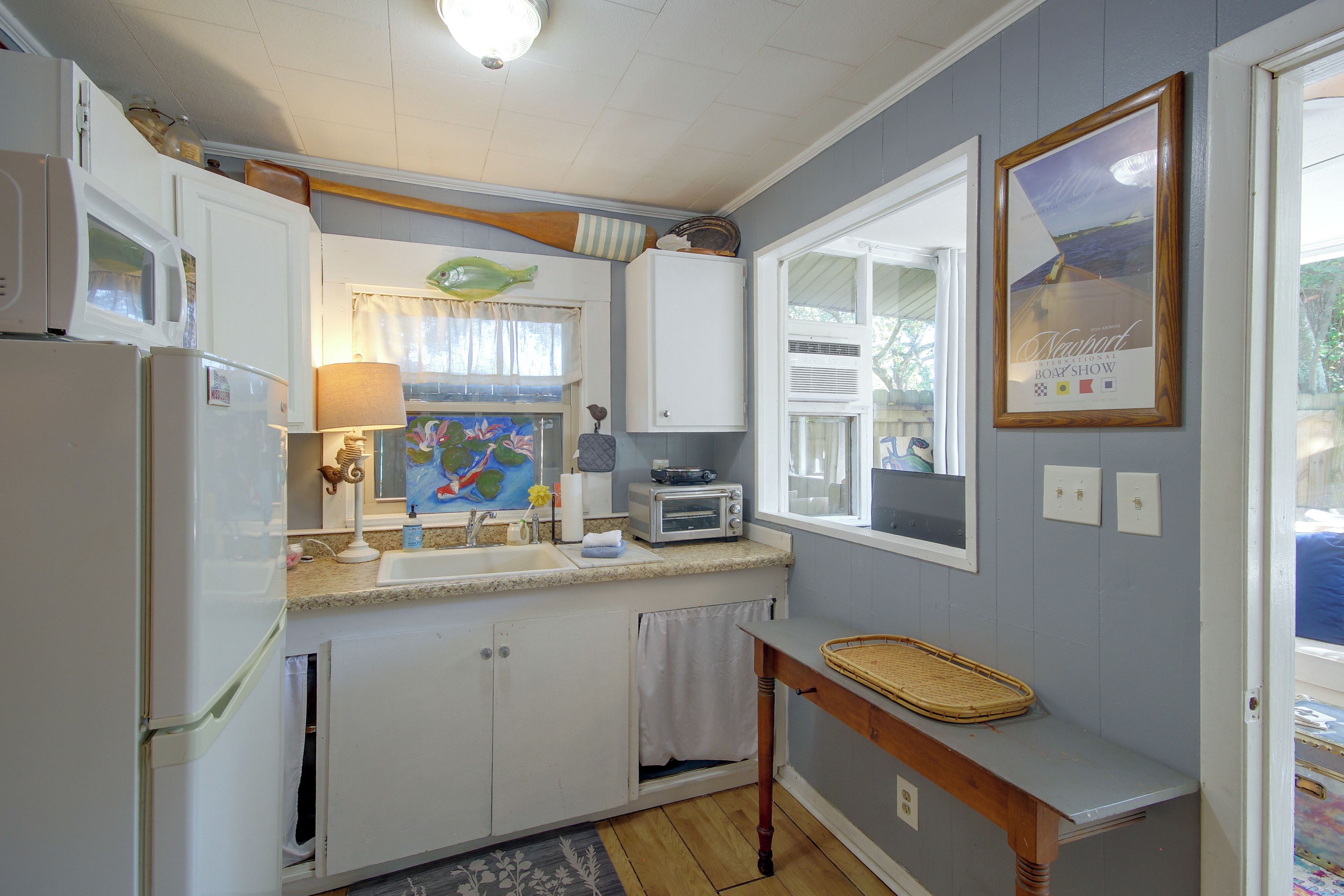 A compact kitchen with white cabinets, a microwave, a toaster, and a window with a view of the outdoors.