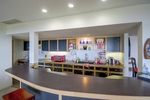 A modern kitchen with a curved island, built-in cabinets, and a variety of appliances. - Sound View, Hot Tub Access! Kitsap Peninsula Stay (Hansville)