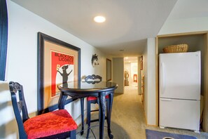 A hallway with a dining area featuring a table and chairs, a refrigerator, and a wall-mounted sculpture. - Sound View, Hot Tub Access! Kitsap Peninsula Stay (Hansville)