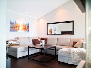 A modern living room with a sectional sofa, a coffee table, and a large mirror.