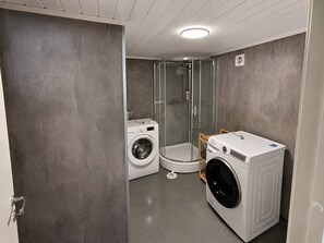 Ein kleines Badezimmer mit Waschmaschine, Duschkabine und Toilette.