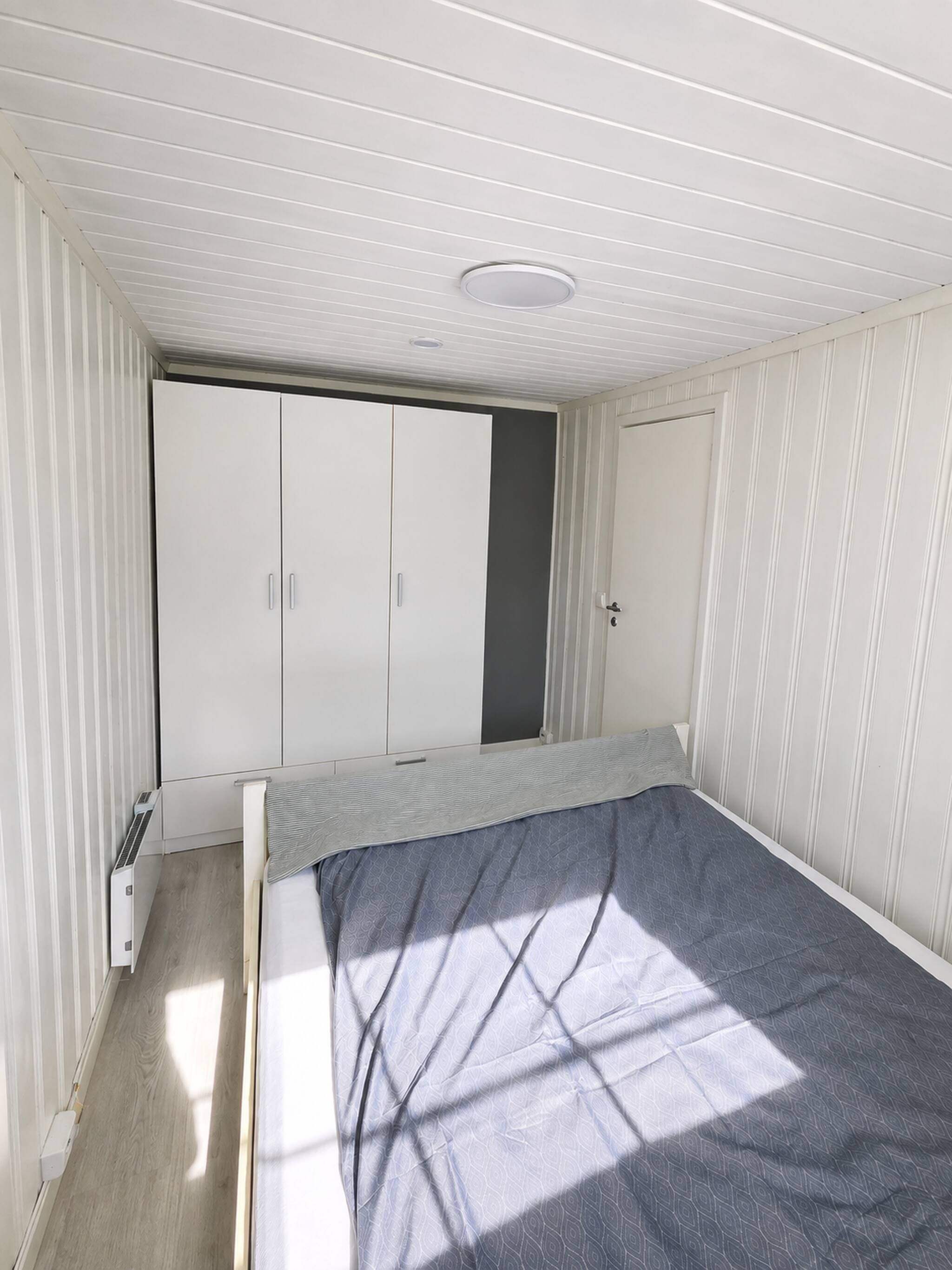 Ein Schlafzimmer mit einem Bett, einem Kleiderschrank und einer Heizung.
