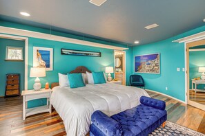 Ein Schlafzimmer mit einem großen Bett, einer blauen Sitzbank und Kunstwerken an den Wänden.