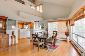 A spacious dining area with a wooden table and chairs, a kitchen in the background, and large windows with blinds. - Families w/ Pets! Mtn-View Parker Home Near Golf (Parker)