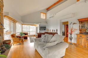 Un salón amplio con un sofá grande, televisor y suelo de madera.