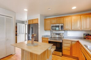 Cocina con armarios de madera, electrodomésticos de acero inoxidable y una isla central.