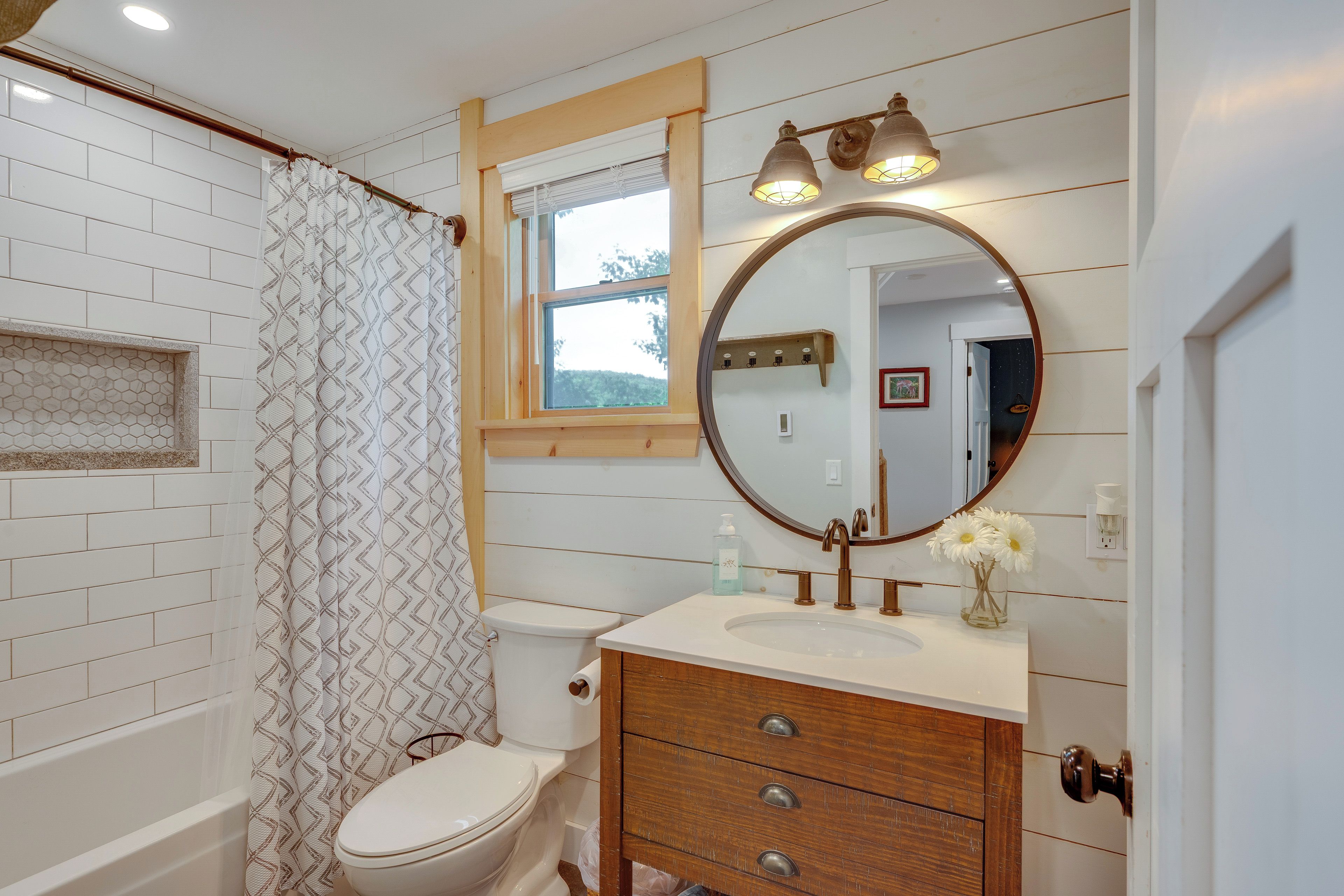 A bathroom with a toilet, sink, vanity, mirror, and shower curtain.