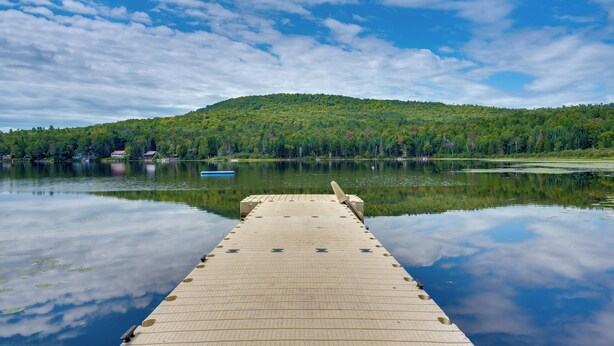 A wooden dock extending into calm water with a forested hill in the background. - On Neal Pond! Spacious Group Retreat w/ Game Room (Lunenburg)