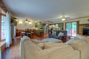 A spacious living room with a large sofa, a dining area with wooden chairs, a kitchen with green cabinets, and a fireplace. - 1/2 Mi to Bull Shoals Lake! Family-Friendly Home (Lakeview)