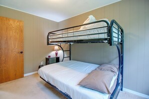 A bunk bed with a single mattress and a pillow, a bedside table with a lamp, and a wooden door. - 1/2 Mi to Bull Shoals Lake! Family-Friendly Home (Lakeview)