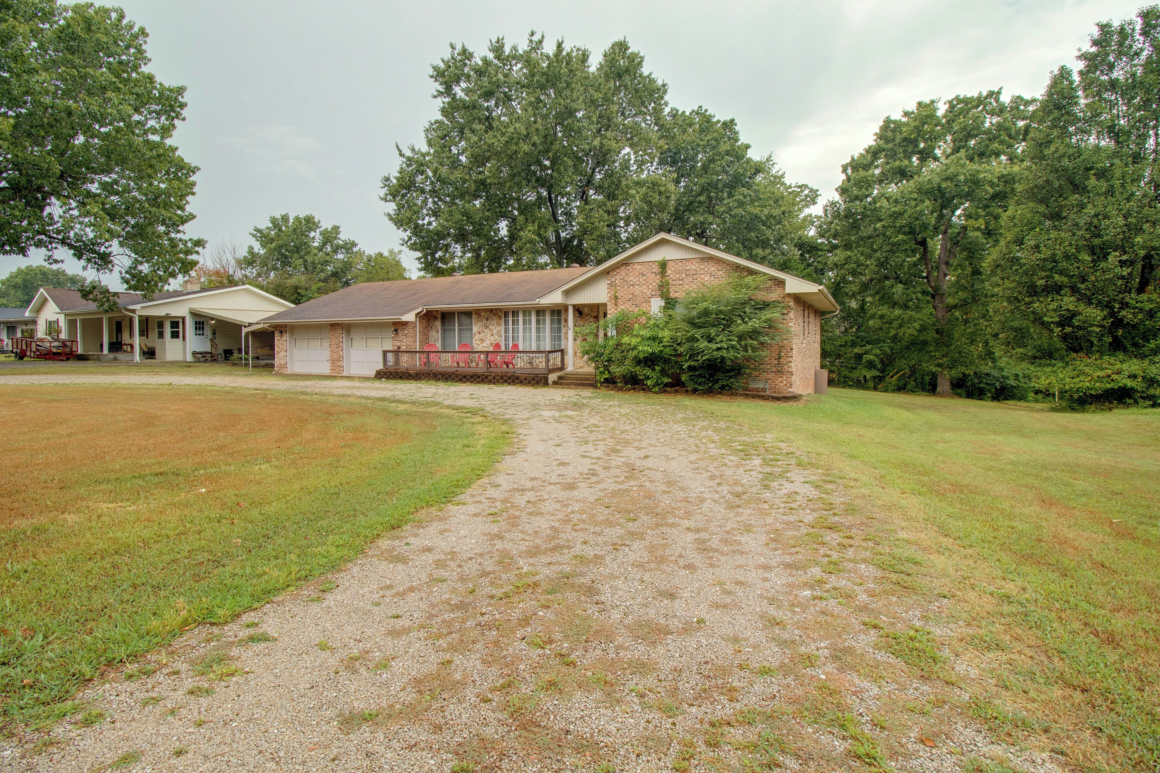 A residential property with a gravel driveway leading to a house with a porch and a garage.