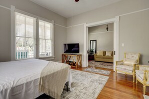 A bedroom with a bed, a television on a wooden stand, a sofa, and a chair. - Historic Jacksonville Home: Near EverBank Stadium (Jacksonville)