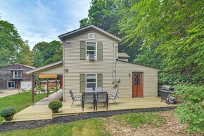 A two-story house with a deck, outdoor seating, and a barbecue grill.