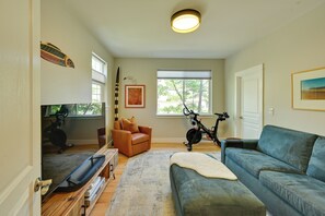 A living room with a sofa, a television, a bicycle, and a window. - Remote Work Ready! Quiet Extended Stay in Bend (Bend)