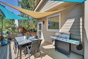 Eine Außenpatio mit Grill, Tisch und Stühlen sowie einem blauen Sonnensegel.