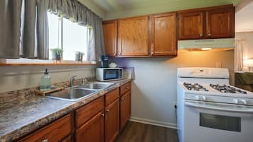 Una cocina con armarios de madera, microondas integrado, estufa y lavaplatos.