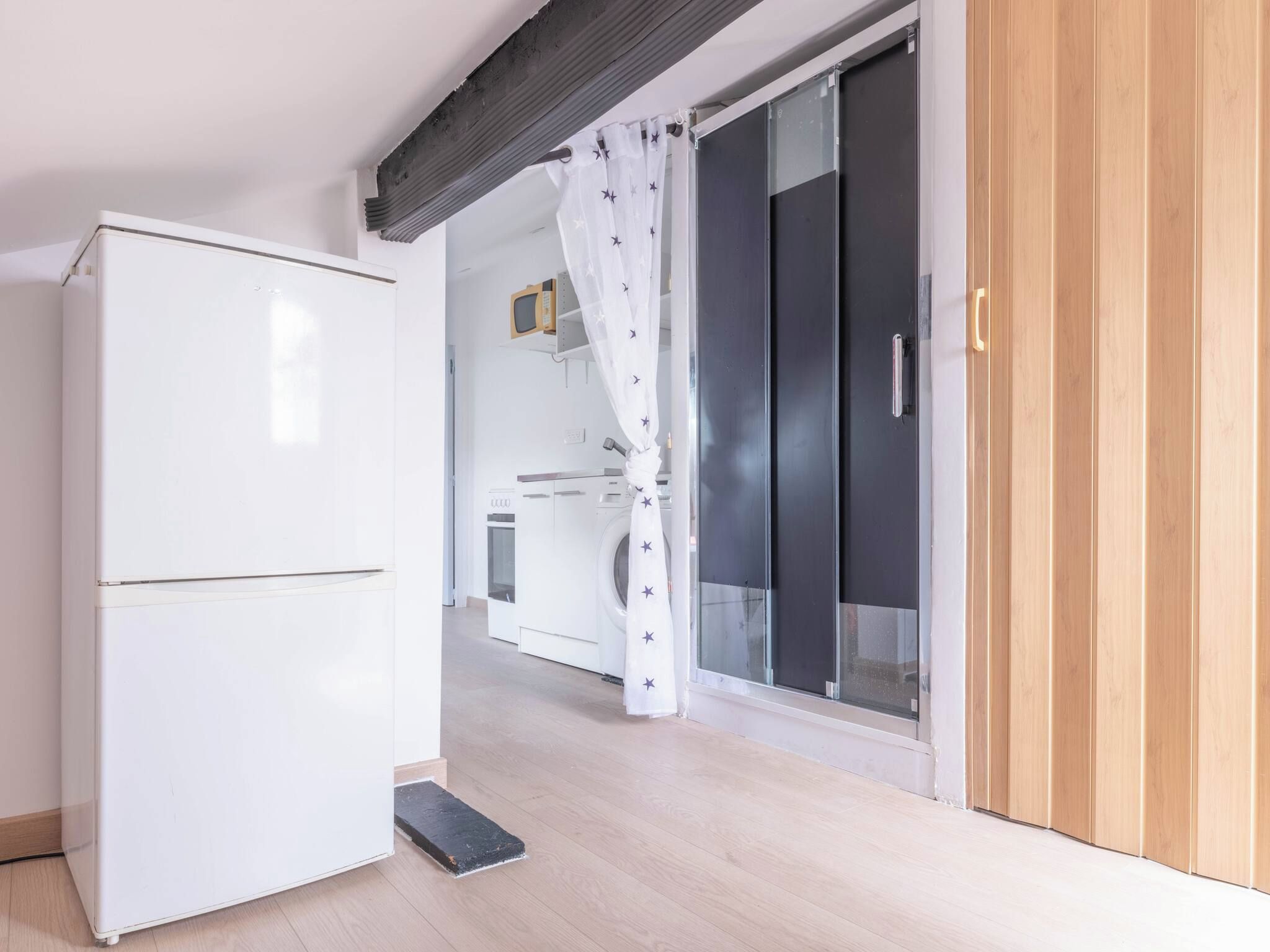 Une cuisine avec un réfrigérateur blanc, un lave-linge et une porte noire.