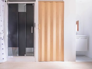 A room with a sliding door, a white cabinet, and a tiled floor. - Renovated studio in the attic — Paris 30 minutes away (Argenteuil)