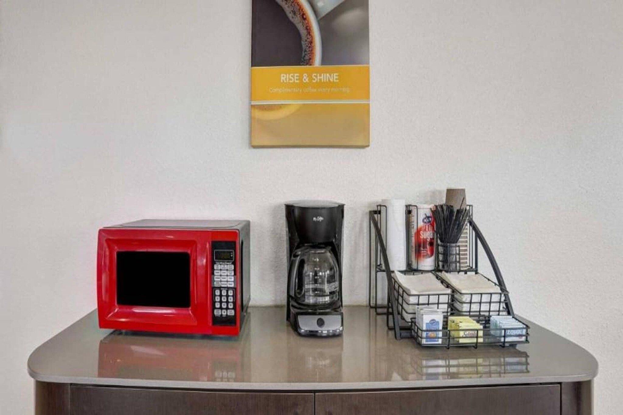 Eine Küchenarbeitsfläche mit einer roten Mikrowelle, einer Kaffeemaschine und einer Körbe voller Küchenutensilien.