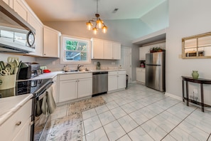 A modern kitchen with white cabinetry, stainless steel appliances, and a patterned rug. - Pet-Friendly Private Yard Near Charleston, Beaches (Goose Creek)