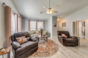 A living room with a leather sofa, a coffee table, a rug, and a ceiling fan. - Pet-Friendly Private Yard Near Charleston, Beaches (Goose Creek)