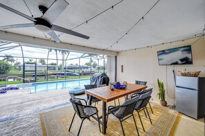Un espace repas moderne avec vue sur la piscine, un ventilateur de plafond et un réfrigérateur.