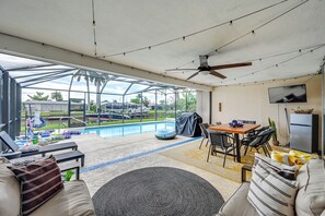 A covered outdoor area with a pool, seating, and a ceiling fan.