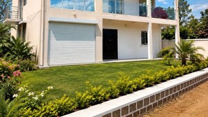 A multi-story building with a garage, a balcony, and a well-maintained lawn. - Modern Apartment • Free WiFi & Airport Transfer (Antananarivo)