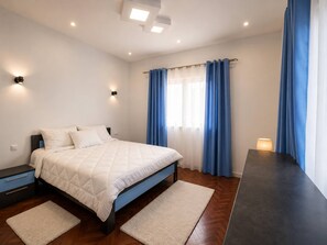 Ein modernes Schlafzimmer mit einem Bett, Nachttischen, einem Schreibtisch und einem Fenster mit Vorhängen.