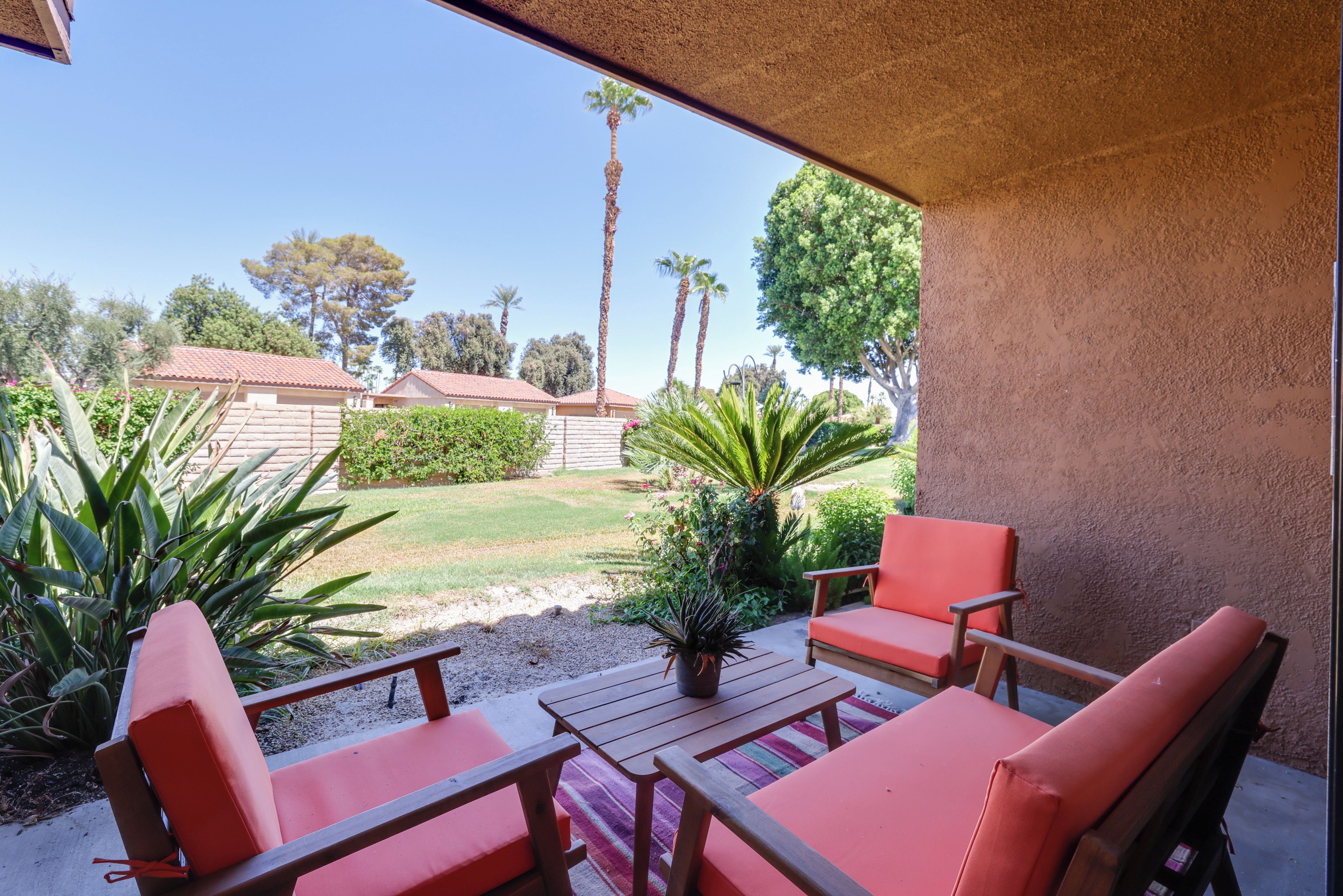 An outdoor patio with wooden furniture and a view of a residential area with palm trees and houses.