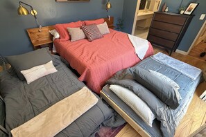 Een slaapkamer met twee bedden, een dressoir, een nachtkastje en een spiegel.